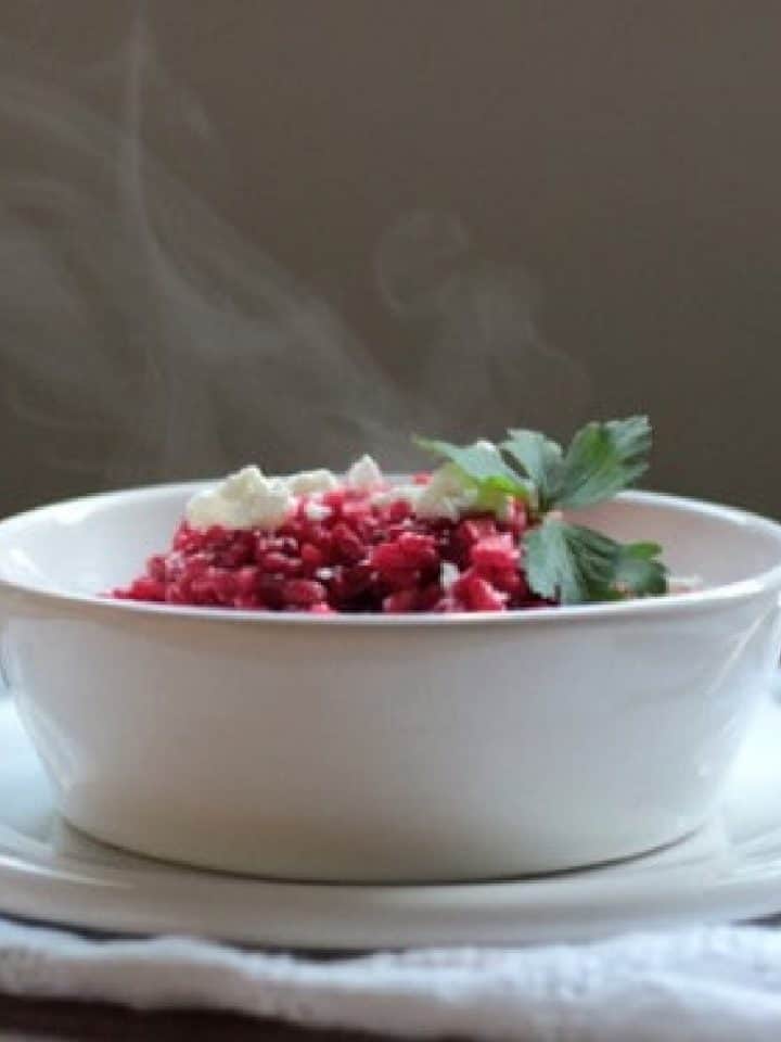 Dark background and white bowl with steaming roasted beet risotto