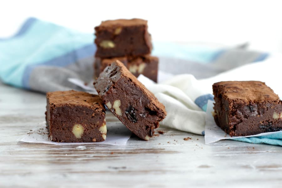 Squares of Whisky raisin walnut Brownies on blue, white, and grey kitchen towels. 