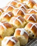 Small buns with white cross on top on a wire rack