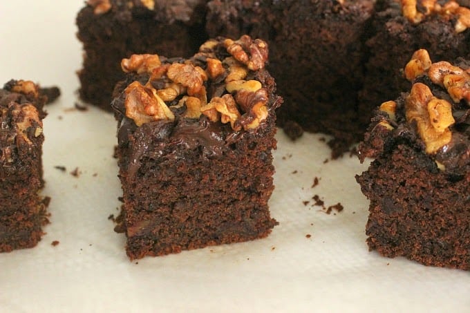 A few chocolate cake squares with walnuts on a white surface