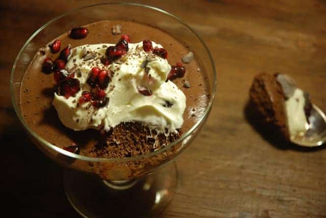 Chocolate Mousse with cream in glass goblet on dark wooden surface.