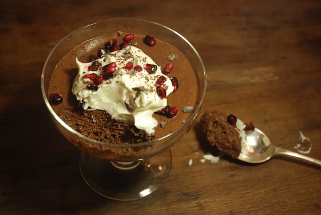 Top view of Chocolate Mousse with whipped cream and pomegranate seeds on glass goblet on wooden tables. 