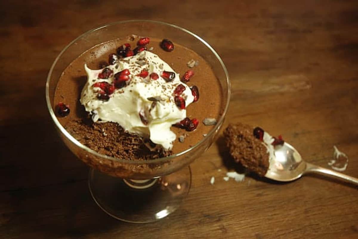 Chocolate Mousse with cream in glass goblet on dark wooden surface.