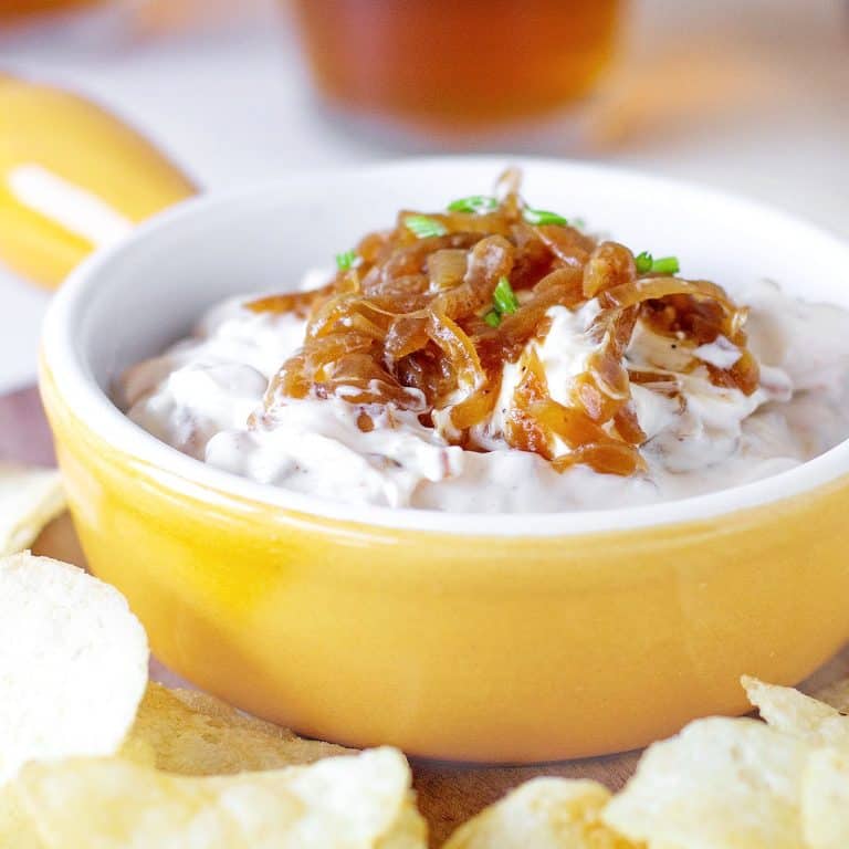 Yellow shallow ramekin with caramelized Onion Dip surrounded by potato chips