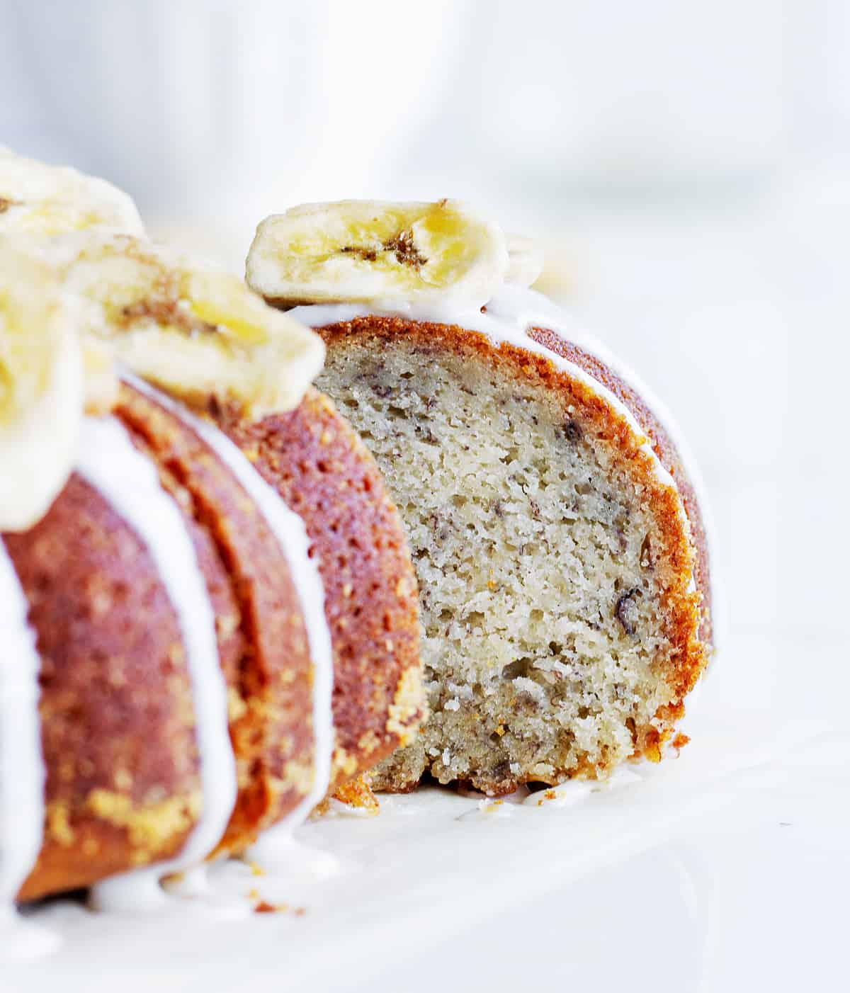Close up of banana bundt slice with blurred rest of cake, whitish background