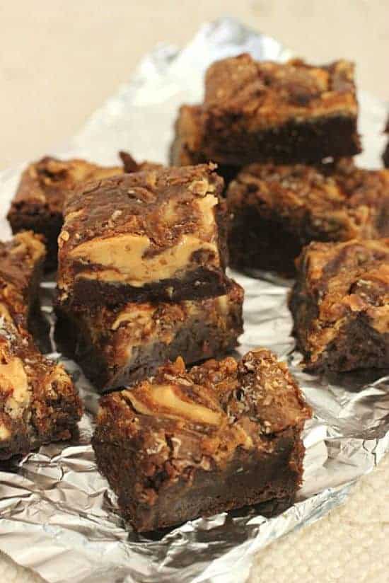 Stacked pieces of swirled brownies on aluminum foil, beige background