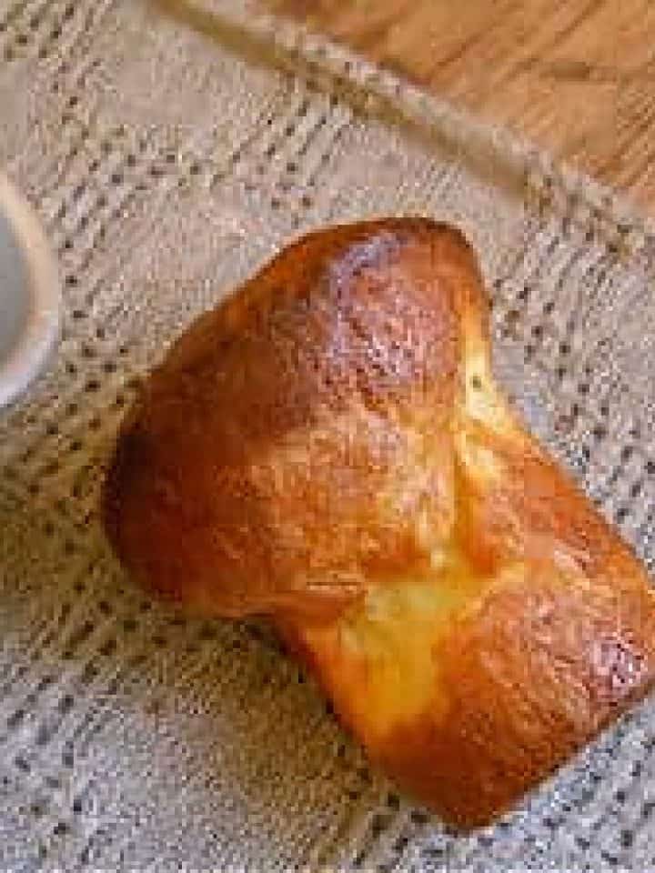 One baked popover on a grey cloth, metal pans beside it.