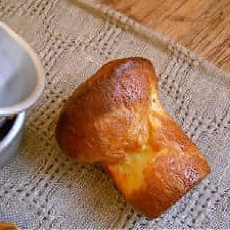 One baked popover on a grey cloth, metal pans beside it.