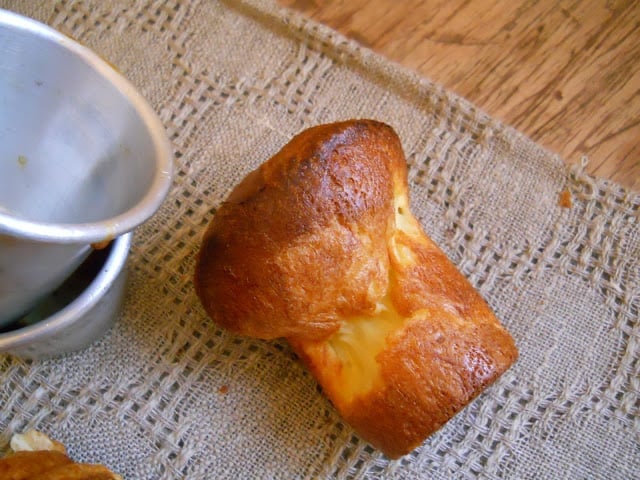 One baked popover on a grey cloth, metal pans beside it.