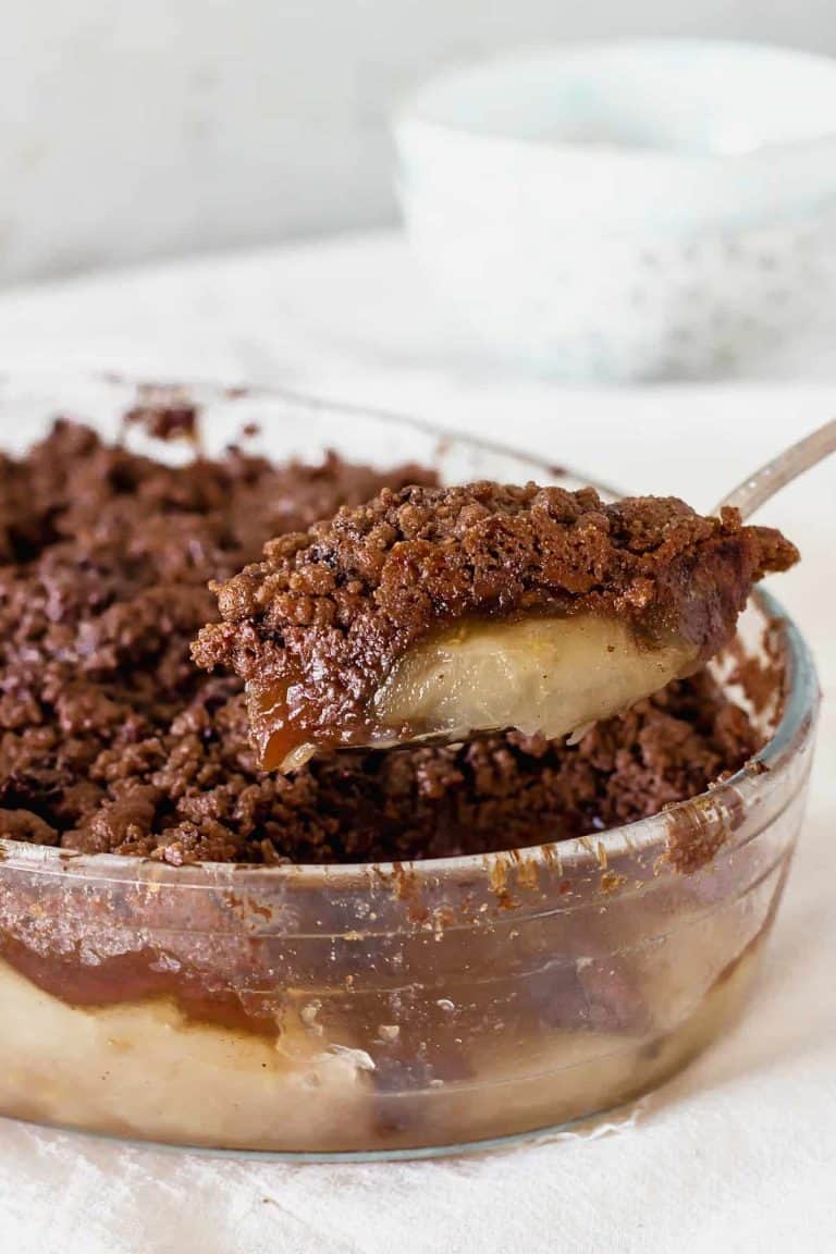 Serving chocolate apple crisp with silver spoon from glass dish