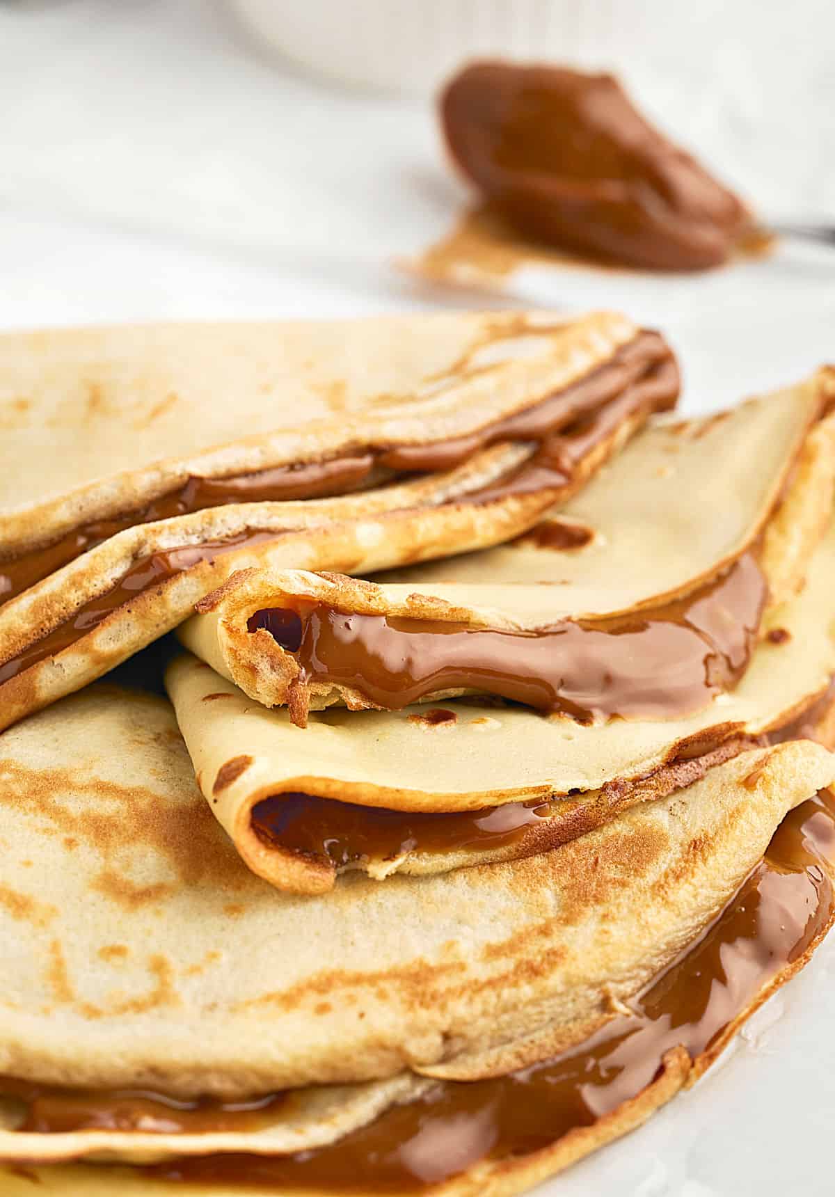 Crepe triangles with dulce de leche on a white plate. Close up view.