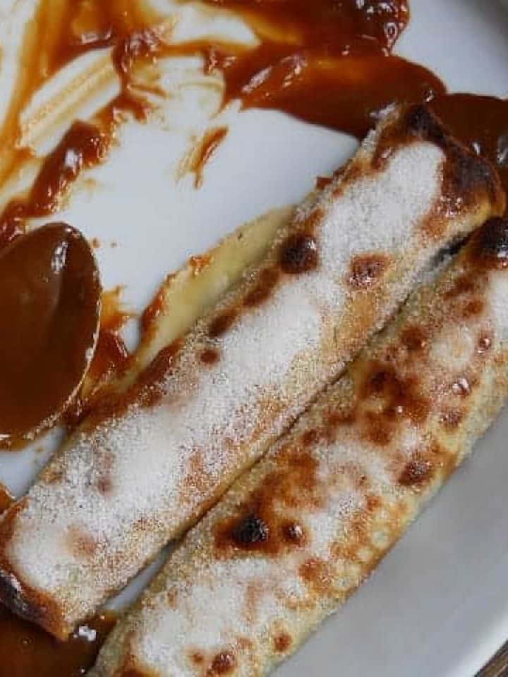 White dish with two dulce de leche crepes and a spoon.