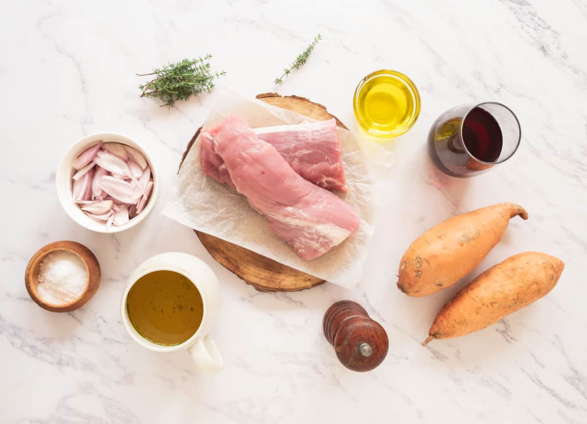 White marble surface with ingredients for pork tenderloin with port thyme shallot sauce and sweet potatoes.