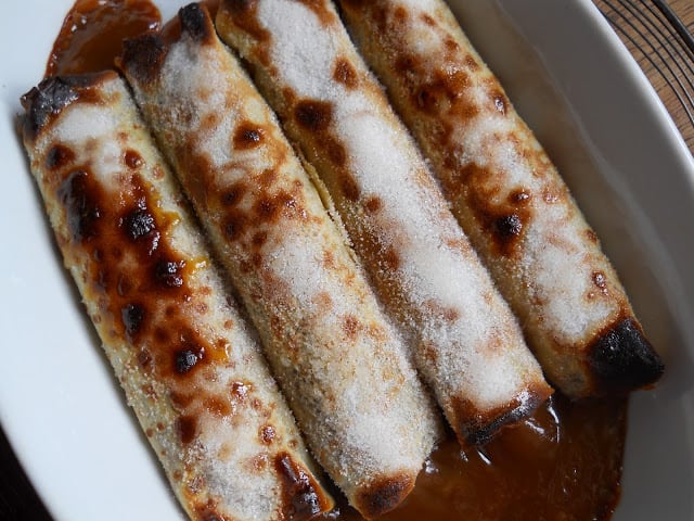 Dulce de Leche Crepes with sugar crust in white ceramic dish. 