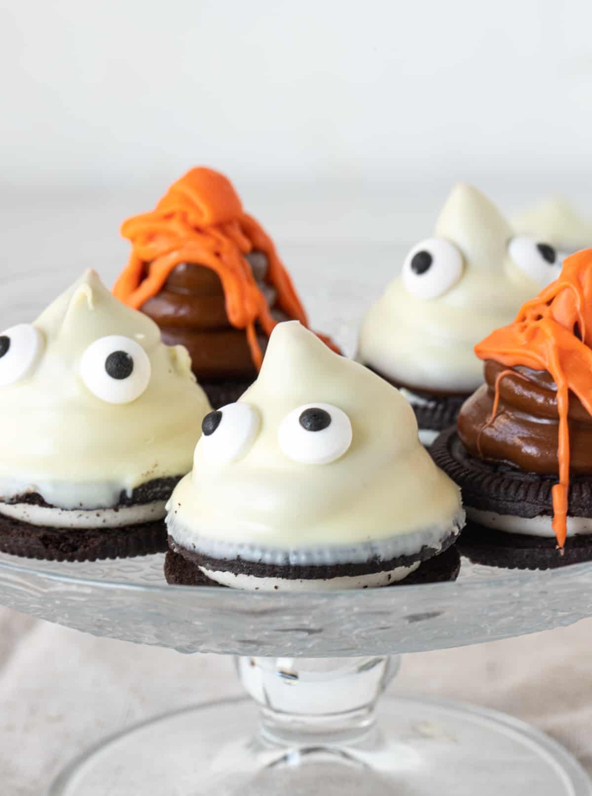 White chocolate and orange cones with candy eyes on a glass plate with a white background. 