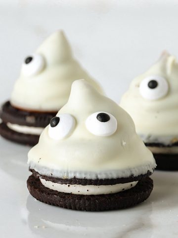 White marble surface with white chocolate cones with candy eyes and oreo cookie base.