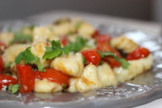 Close up of potato gnocchi with cherry tomatoes and basil on grey plate. 
