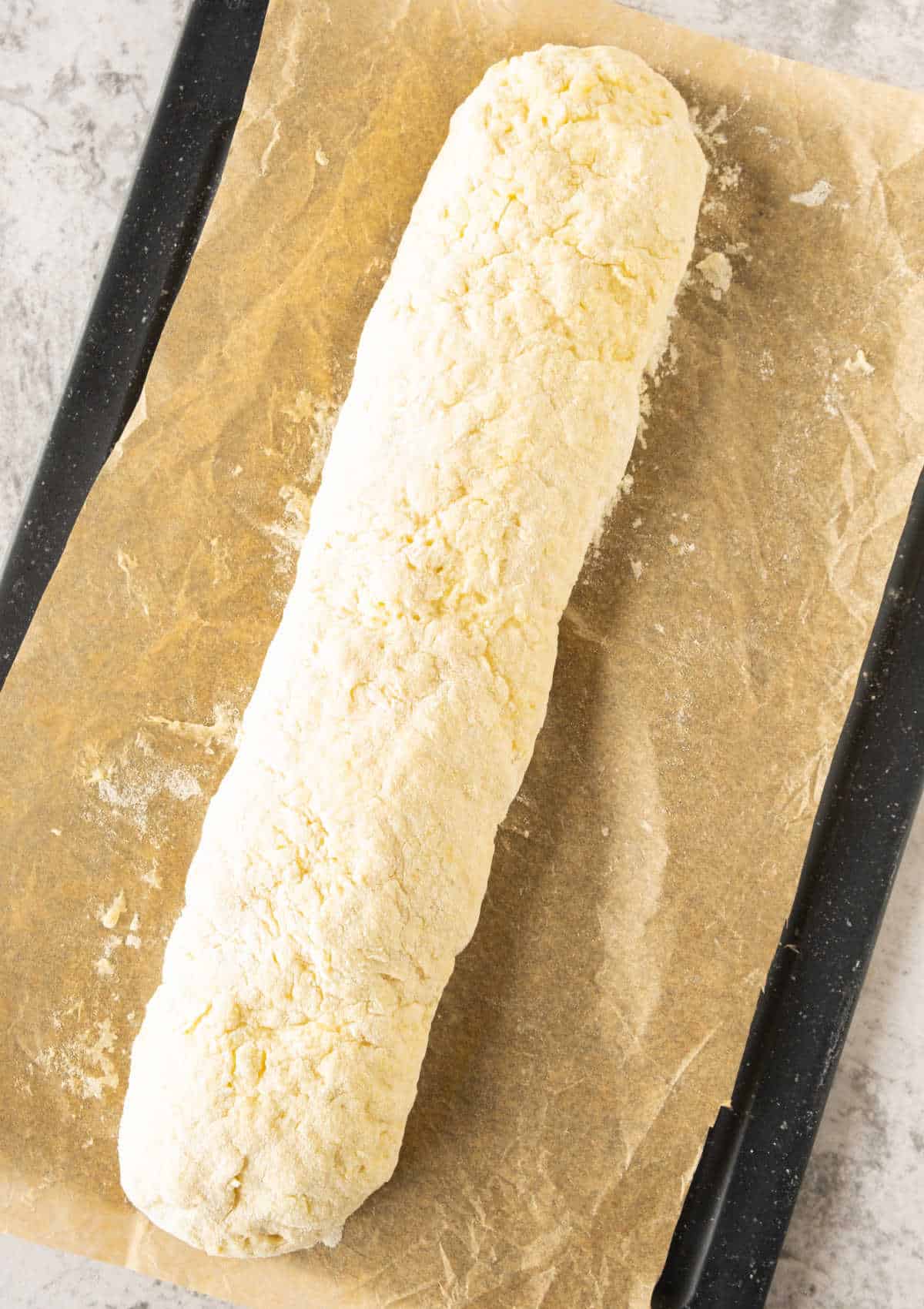 Log of potato gnocchi dough on beige parchment paper.