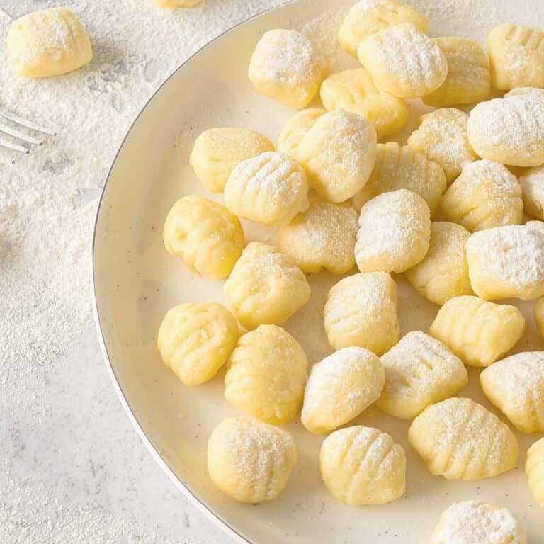 Homemade potato gnocchi before cooking on a white plate.