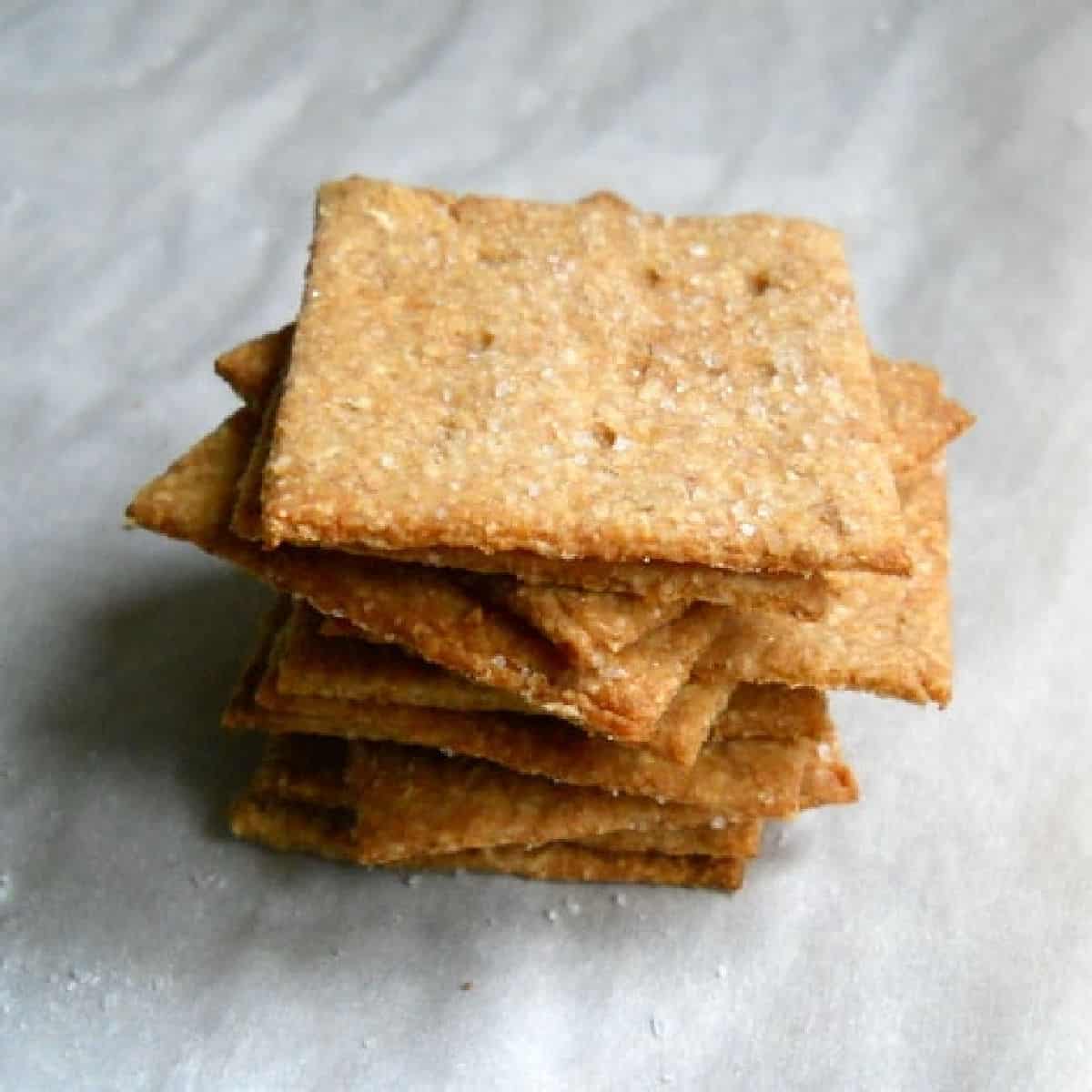 Stack of wheat thin crackers on parchment paper.