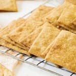 Close up wire rack with overlapping homemade crackers. White surface.