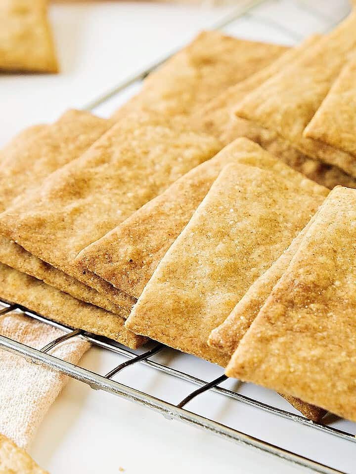 Close up wire rack with overlapping homemade crackers. White surface.