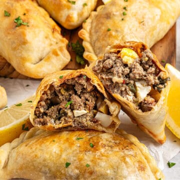 Halved beef empanada on a pile of whole ones.