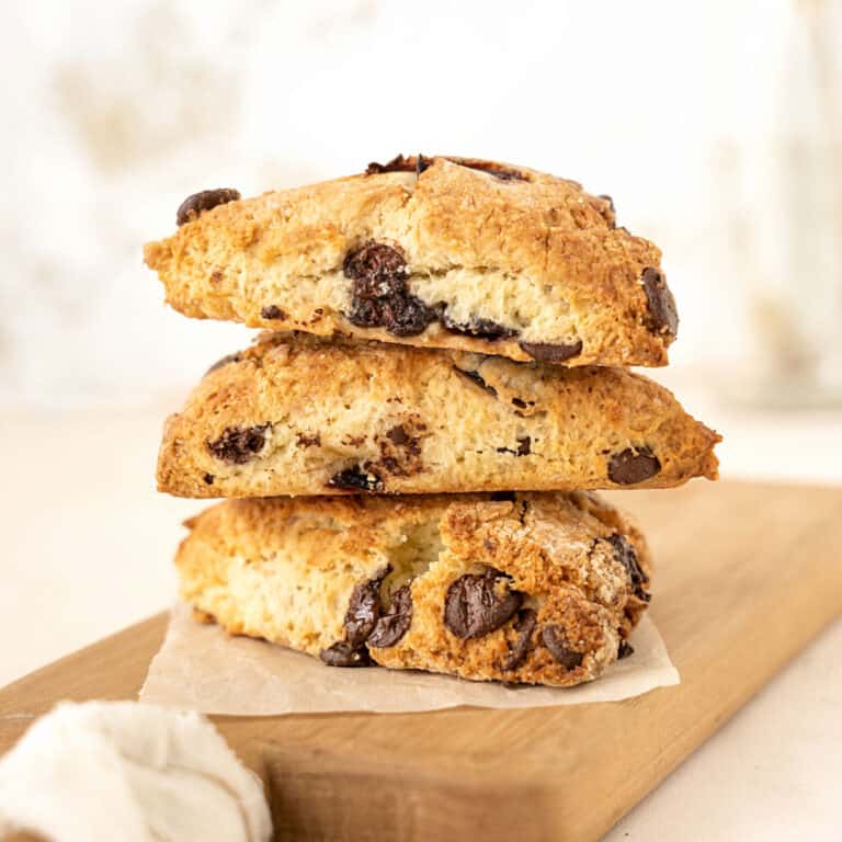 Wooden board with three chocolate chunk cherry scones stacked. White beige background.