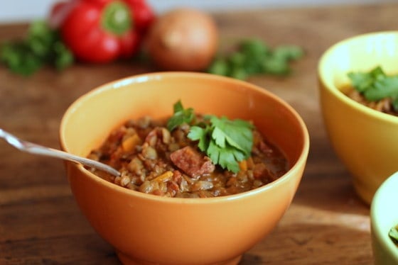 Orange bowl of Lentil Stew with a spoon, wooden table