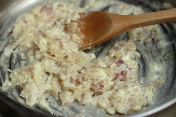 Cooking white sauce with onion in a metal skillet.