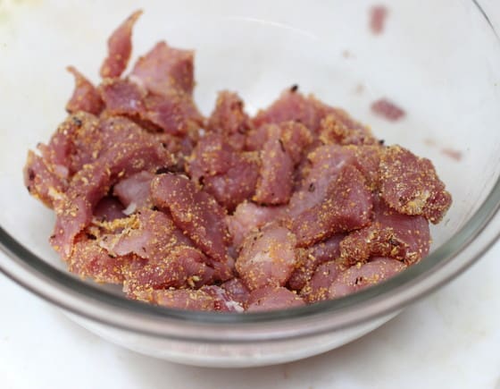 Glass bowl with pork pieces in cornmeal.