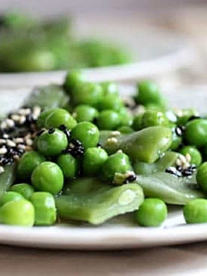 Very close up image of a mound of sesame peas and green beans on a plate.