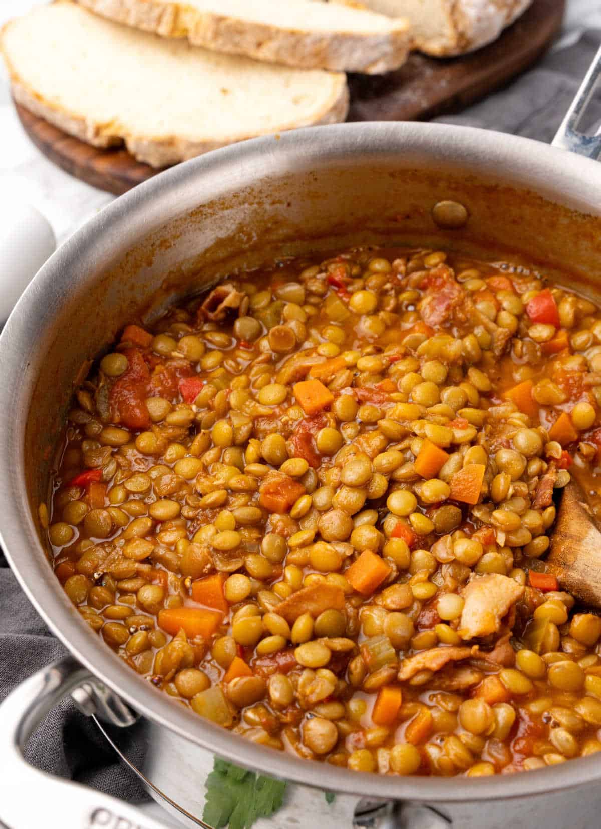 Large metal pot with lentil stew. Bread slices in the background.
