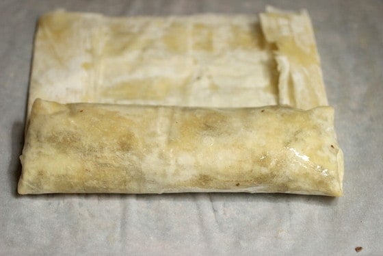 Assembling phyllo dough strudel on a white cloth.