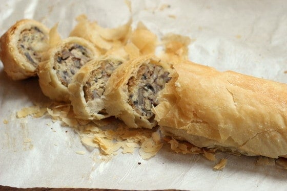 Baked mushroom strudel with cut slices on a white paper.
