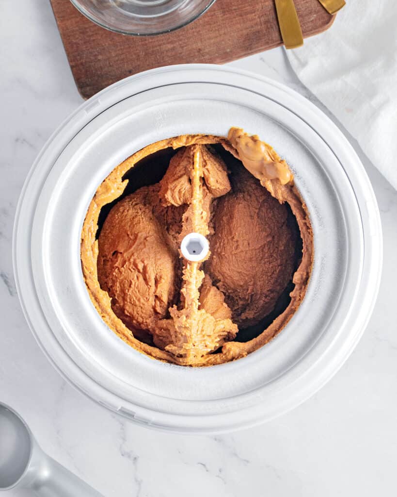 Ice cream machine bowl with churned brown sugar ice cream. Top view. Light gray background.