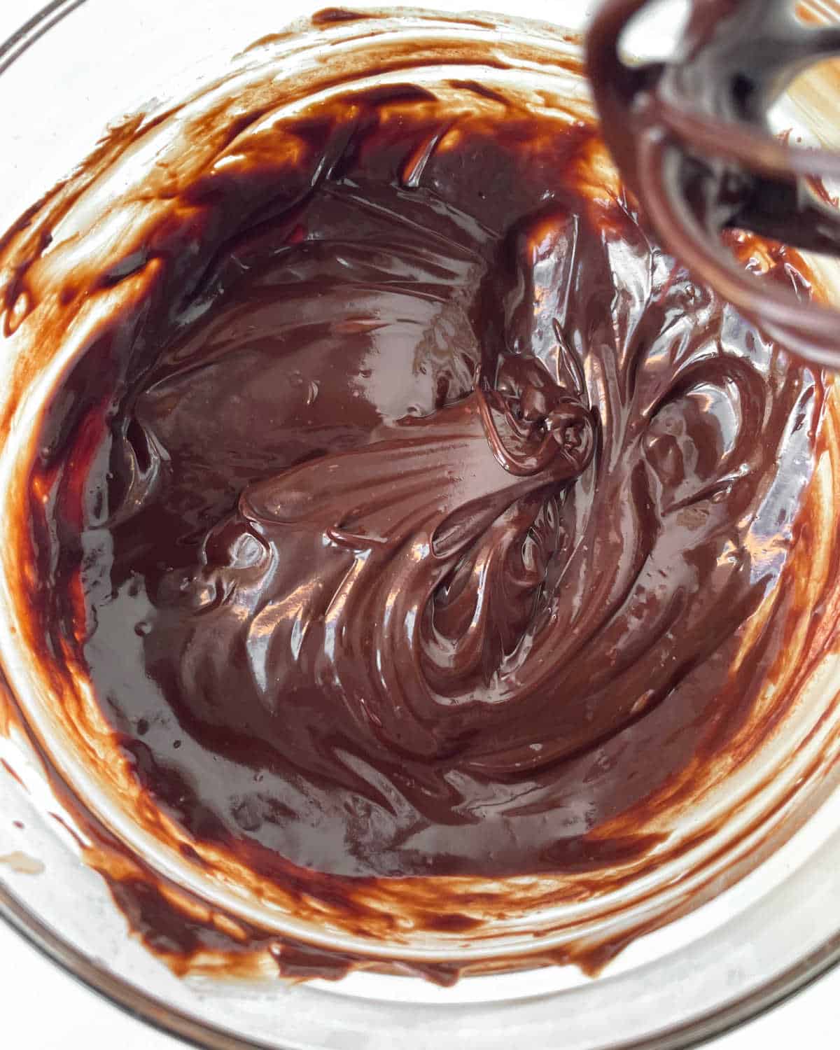 Close up of chocolate ganache coating in a glass bowl.