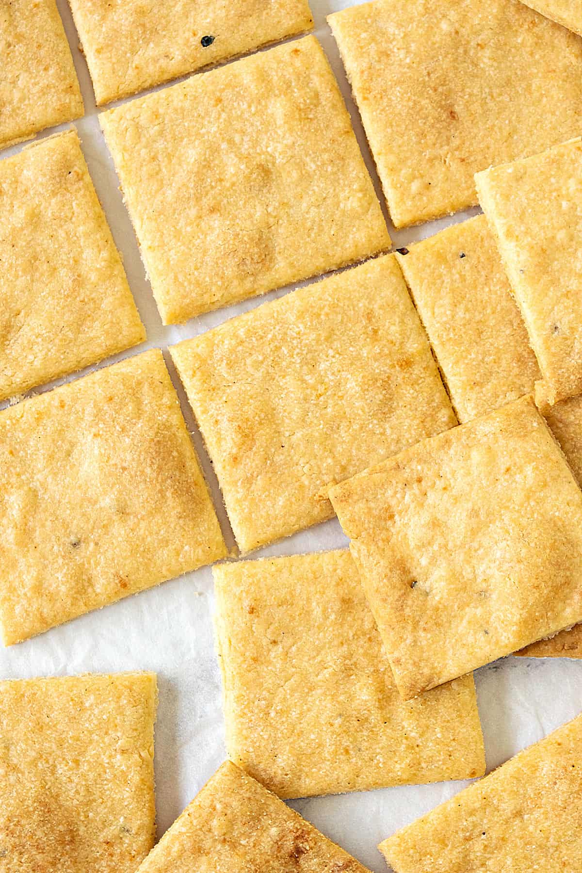 Rows of cheese crackers on a white surface. Close up view.