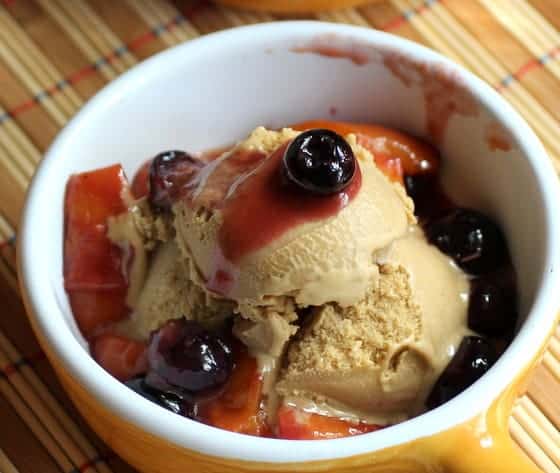 Caramelized fruit with brown sugar ice cream in white yellow ramekin on a bamboo placing mat. 