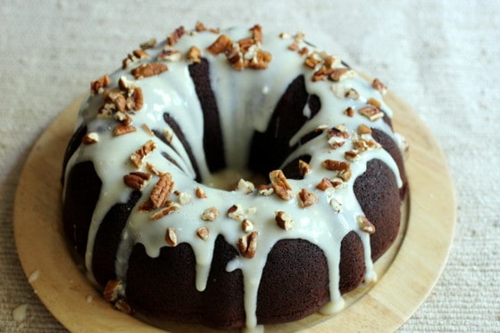 Whole glazed Chocolate Bundt Cake on a wooden plate.