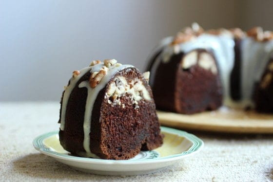 Chocolate Bundt Cake slice in a plate, rest of cake blurred in background.