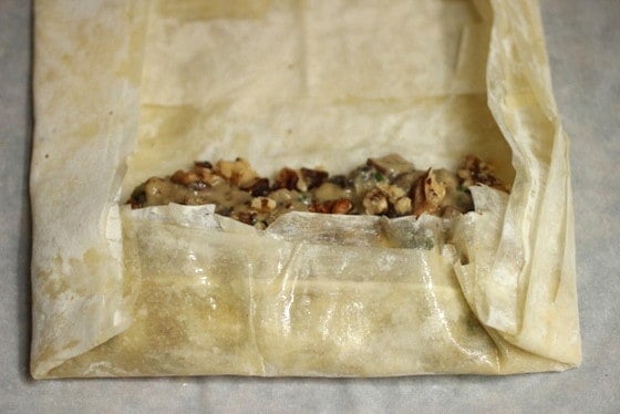 Phyllo dough on a grey surface encasing part of the mushroom filling.