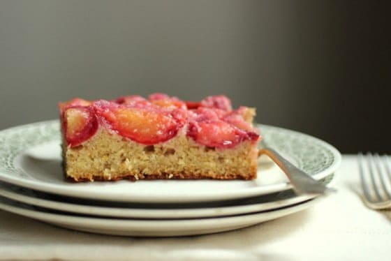 Plum cake on stack of white and green plates.