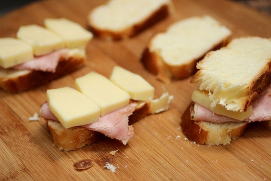 Bamboo board with ham and cheese sandwiches.