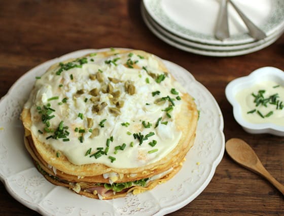 Top view of mayonnaise topped Crêpe Cake on white plate, wooden table.