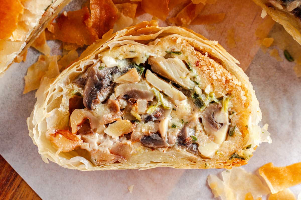 Single slice of close up mushroom phyllo strudel on white paper.