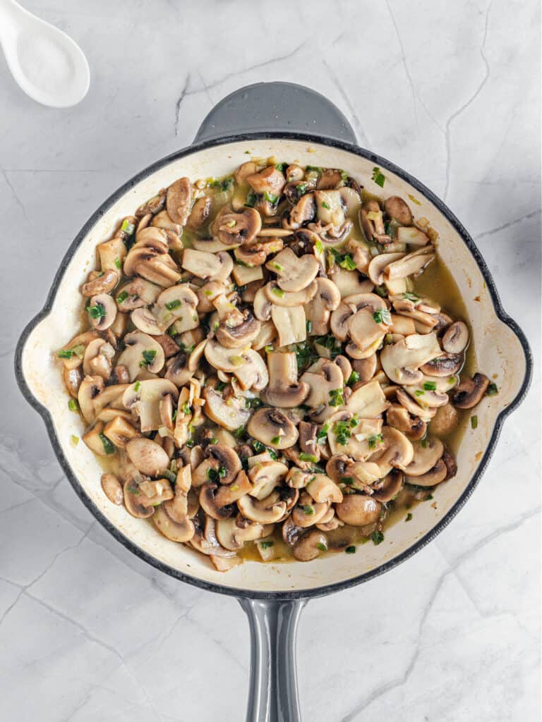 Gray and white skillet with mushroom filling. White marble surface, top view.