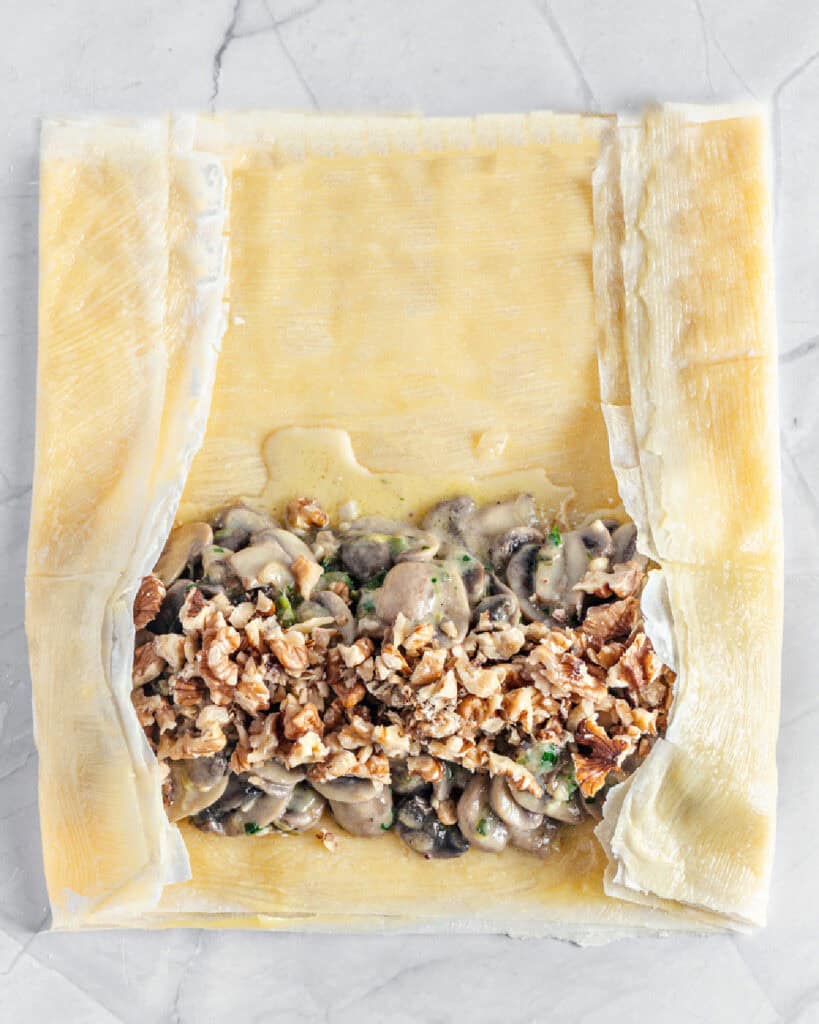 Buttered phyllo sheets with mushroom filling before rolling.