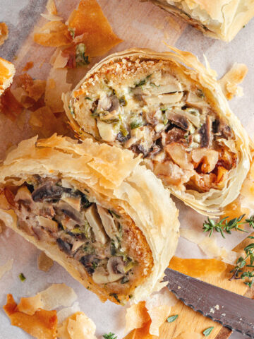 Close up slices of mushroom strudel on white parchment paper. Thyme sprigs.