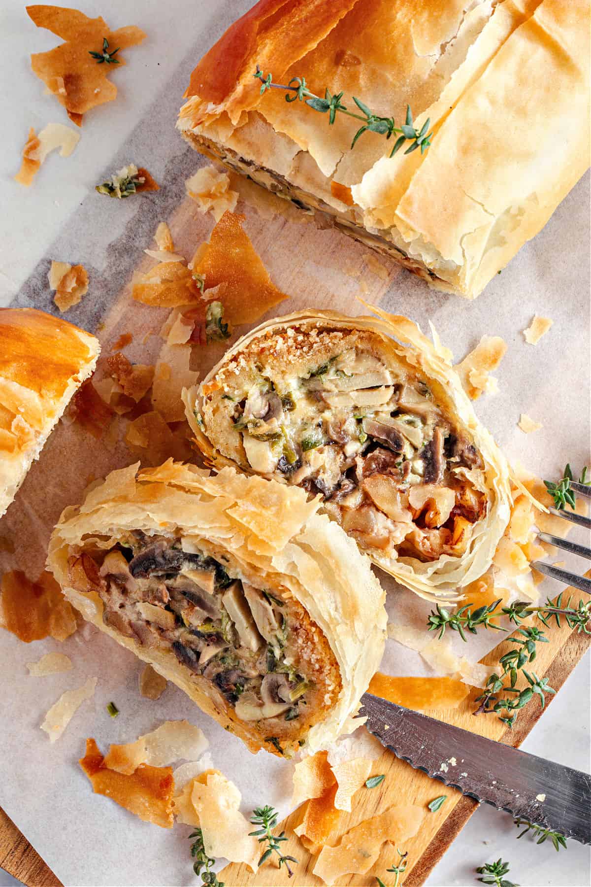 Mushroom Cheese Strudel Slices of mushroom strudel on white parchment paper. Thyme sprigs.